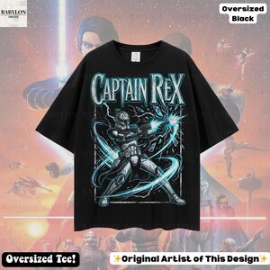 May include: Black oversized t-shirt with a graphic of Captain Rex from Star Wars, and the text "CAPTAIN REX". The design shows the character in action with blue energy effects. The shirt has the text "Oversized Tee!" and "Original Artist of This Design".