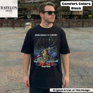 May include: Black t-shirt featuring a Star Wars movie poster design with Japanese text. The shirt has a crew neck and short sleeves. The text "Comfort Colors Black" is visible in the upper right corner.