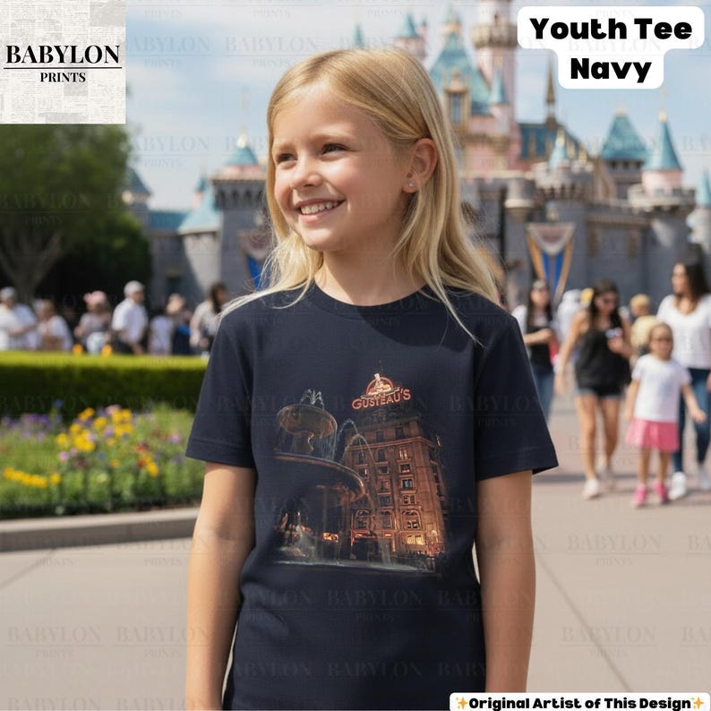 May include: Navy blue youth tee with a graphic of a building and the text "GUSTEAU'S". The tee is a crew neck style. The words "Youth Tee Navy" are printed in white. The shirt is worn by a young person. The image is taken outdoors.