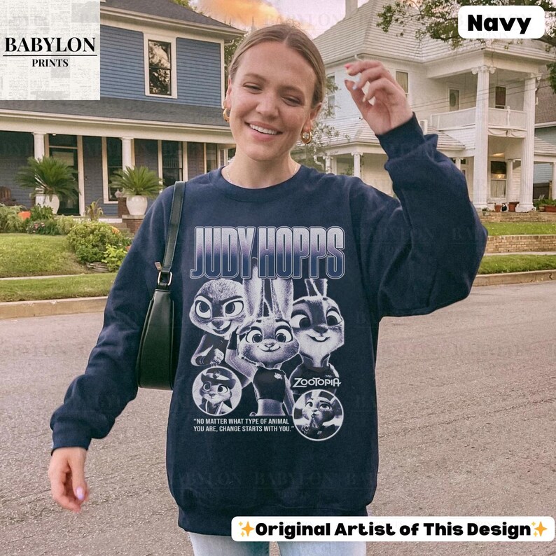 May include: Navy blue sweatshirt featuring the text "JUDY HOPPS" and images of characters from the movie Zootopia. The sweatshirt also includes the text "NO MATTER WHAT TYPE OF ANIMAL YOU ARE, CHANGE STARTS WITH YOU." and "ZOOTOPIA."