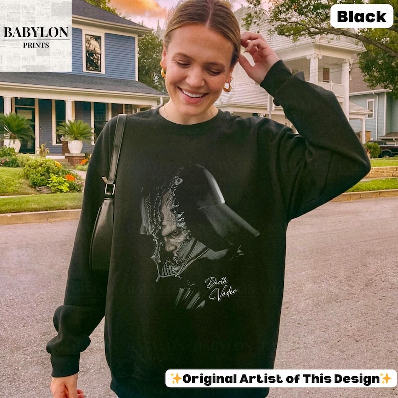 K&ouml;nnte beinhalten: Schwarzes Sweatshirt mit Darth Vader-Grafik. Das Design zeigt eine detaillierte Illustration von Darth Vaders Helm und Gesicht mit dem Text "Darth Vader". Das Sweatshirt stammt von "Babylon Prints".