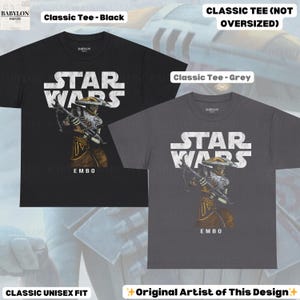 Puede incluir: Camisetas cl&aacute;sicas negras y grises con un dise&ntilde;o de Star Wars. El texto "STAR WARS" es blanco. Las camisetas muestran una ilustraci&oacute;n de personaje y el nombre "EMBO". Corte unisex cl&aacute;sico.
