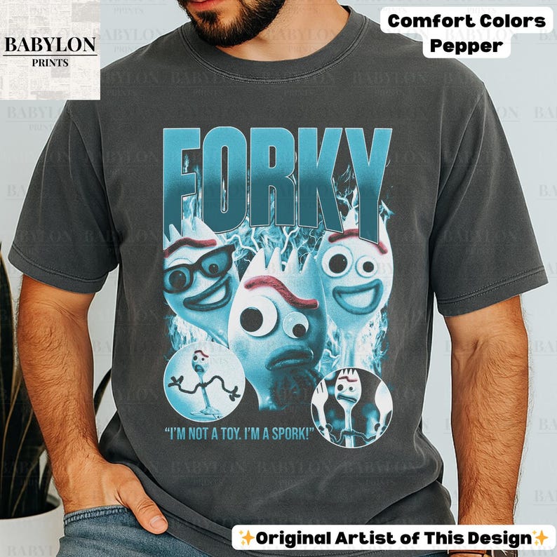 May include: Dark gray t-shirt featuring the word "FORKY" in a gradient blue font, with cartoon spork characters. The shirt includes the text "I'M NOT A TOY. I'M A SPORK!" and the words "Comfort Colors Pepper".