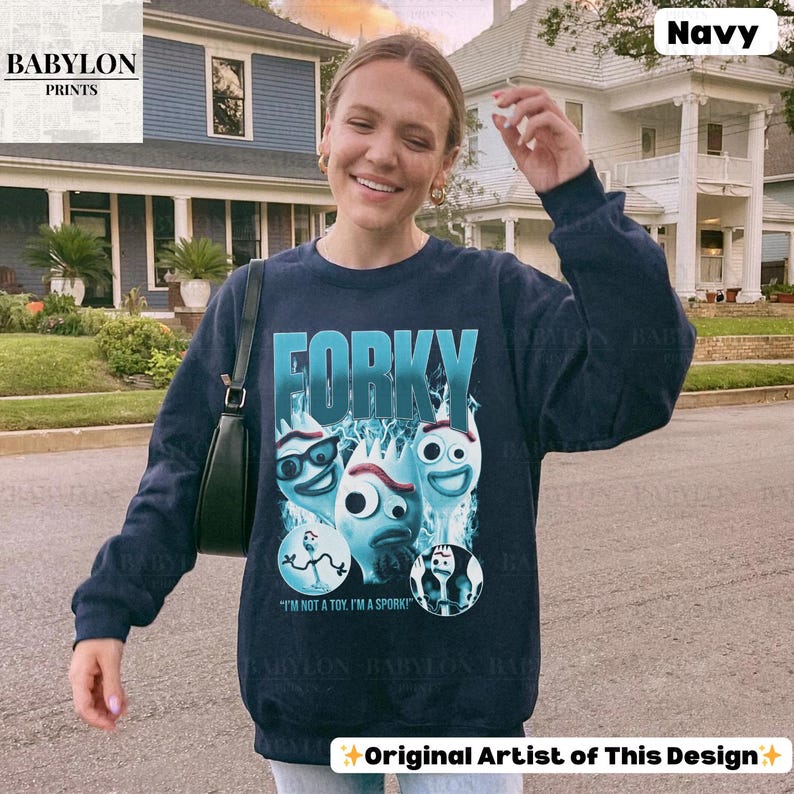May include: Navy blue sweatshirt featuring the word "FORKY" in a turquoise font, with cartoon character graphics. The sweatshirt also has the text "I'M NOT A TOY, I'M A SPORK!" and the Babylon Prints logo.