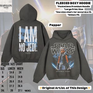 May include: A dark gray fleeced boxy hoodie with the text "I AM NO JEDI" on the back and a Star Wars graphic on the front. The front graphic features Ahsoka Tano with blue lightsabers. The hoodie is unisex.