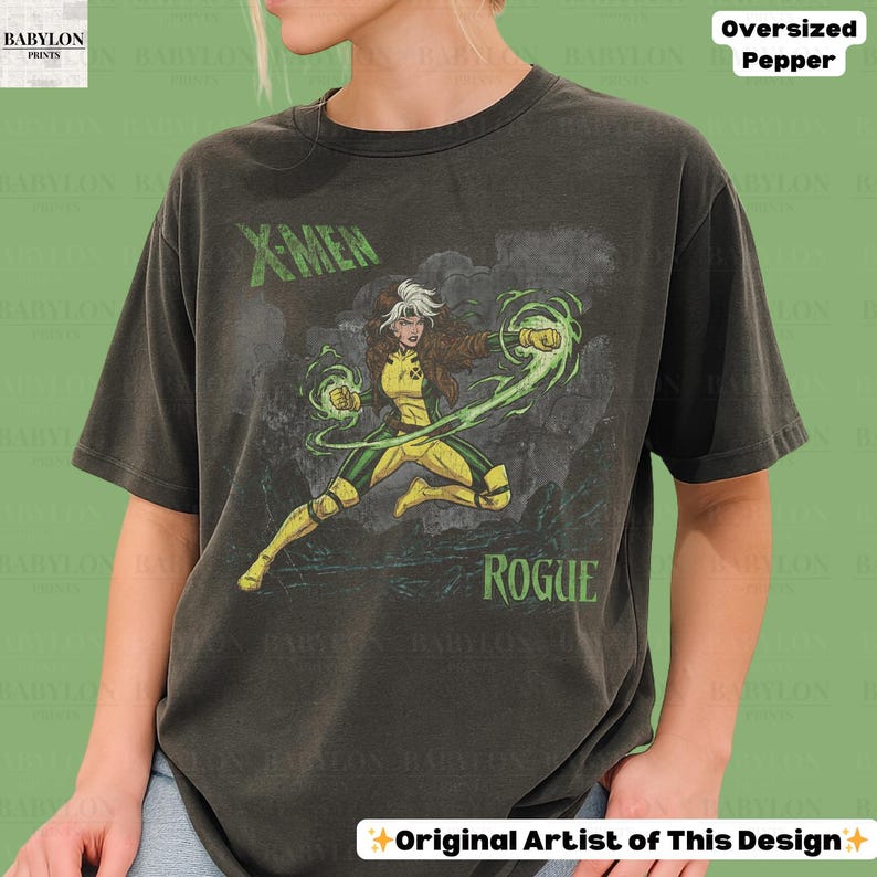 May include: Dark grey oversized t-shirt with a graphic of Rogue from X-Men. The design includes the text "X-MEN" and "ROGUE" in green. The character is shown in a dynamic pose with green energy effects.
