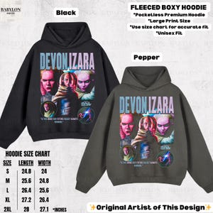 Pu&ograve; includere: Felpe con cappuccio boxy in pile nere e color pepe con un design a stampa grande. Il design presenta il testo "DEVON IZARA" e una grafica di una persona. Le felpe con cappuccio hanno un design senza tasche e sono disponibili in varie taglie.