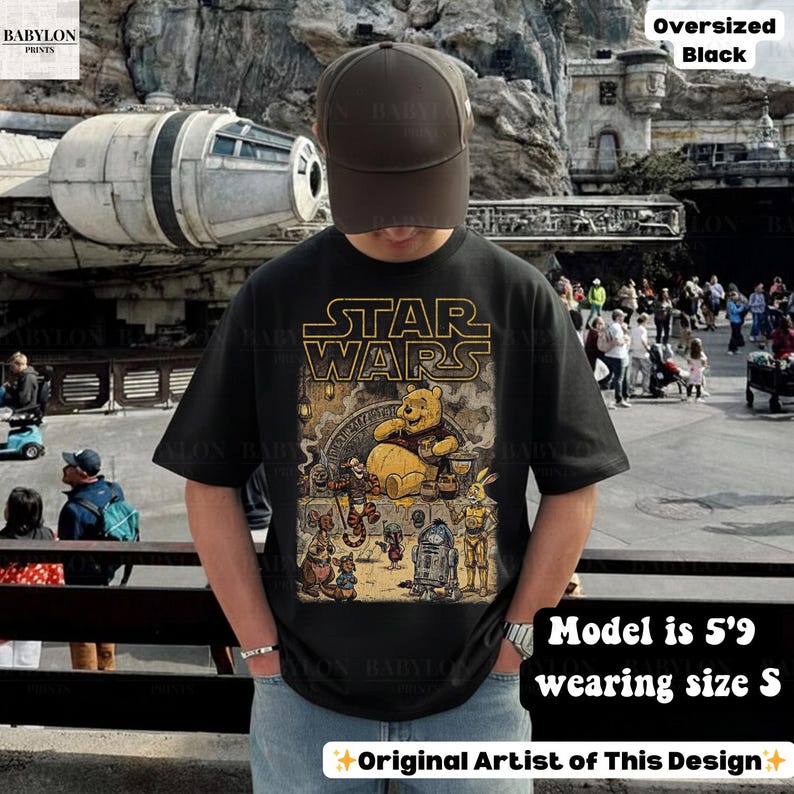 Może przedstawiać: Czarny, obszerny t-shirt z grafiką Star Wars i Kubusia Puchatka. Projekt zawiera napis "STAR WARS" złotymi literami. Modelka ma 175 cm wzrostu i nosi rozmiar S.