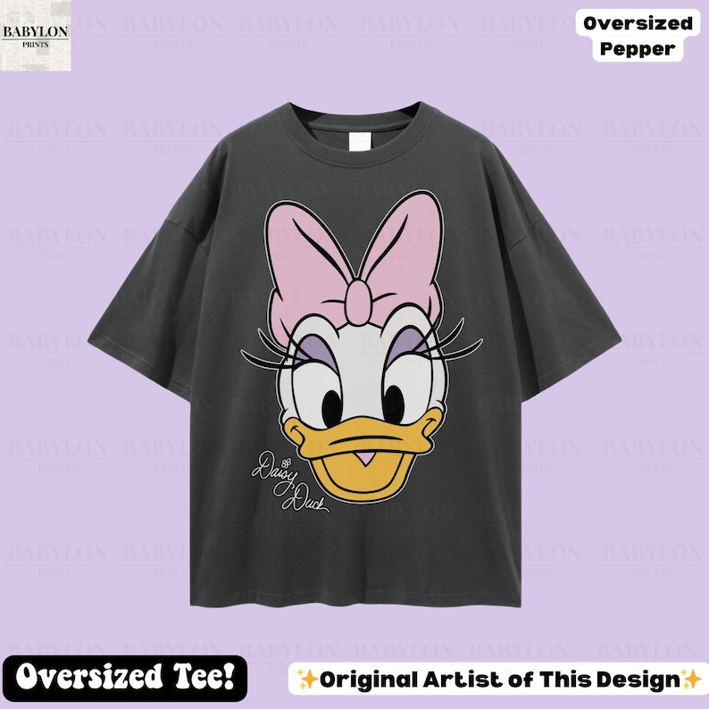 Puede incluir: Camiseta gris oscuro de gran tama&ntilde;o con un gran gr&aacute;fico de Daisy Duck con un lazo rosa, pesta&ntilde;as y un pico amarillo. El texto "Daisy Duck" est&aacute; escrito en cursiva. La camiseta tiene el texto "Oversized Tee!" y "Original Artist of This Design".
