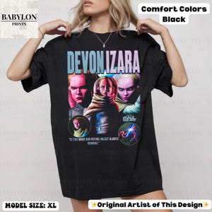 Pu&ograve; includere: T-shirt nero oversize con il nome "DEVON IZARA" in un font sfumato. La maglietta presenta una grafica di una persona con pi&ugrave; volti e il testo "IS THIS WHAT OUR FUTURE HOLDS? ALWAYS RUNNING." La maglietta &egrave; etichettata "Comfort Colors."