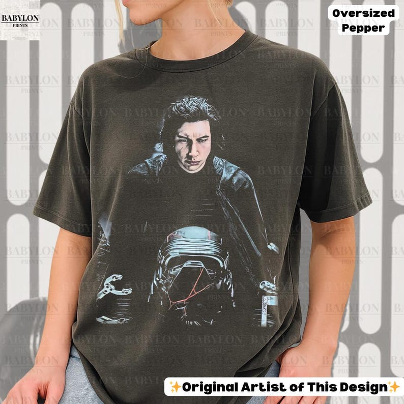 May include: Dark grey oversized t-shirt with a graphic of a person and a helmet. The text "Oversized Pepper" is at the top right. The words "Original Artist of This Design" are at the bottom.