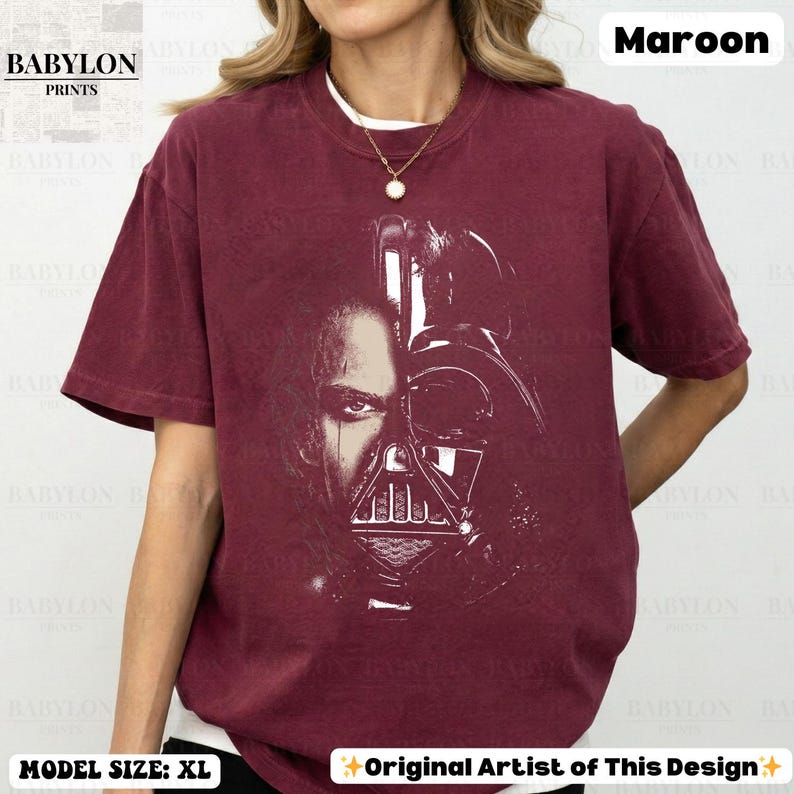 May include: Maroon t-shirt featuring a split image of a person and Darth Vader's helmet. The shirt has the text "BABYLON PRINTS" and "Original Artist of This Design". The model is wearing a size XL.