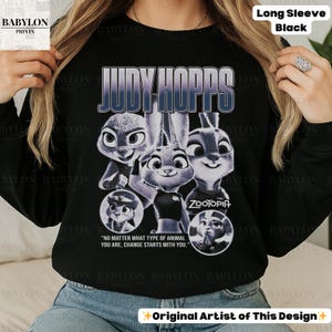 May include: Black long-sleeve shirt featuring a graphic of Judy Hopps from Zootopia. The design includes the text "JUDY HOPPS" and the quote "NO MATTER WHAT TYPE OF ANIMAL YOU ARE, CHANGE STARTS WITH YOU."