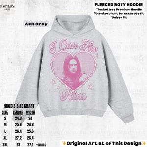 May include: Ash grey fleece boxy hoodie with a pink graphic of a man inside a heart with the text "I Can Fix Him". The hoodie has a hood and a size chart. Unisex fit. Made of a soft material.