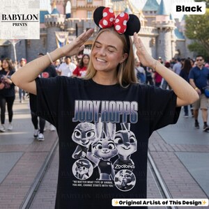 May include: Black t-shirt featuring the text "JUDY HOPPS" and images of characters from the movie Zootopia. The shirt also includes the quote "NO MATTER WHAT TYPE OF ANIMAL YOU ARE, CHANGE STARTS WITH YOU."