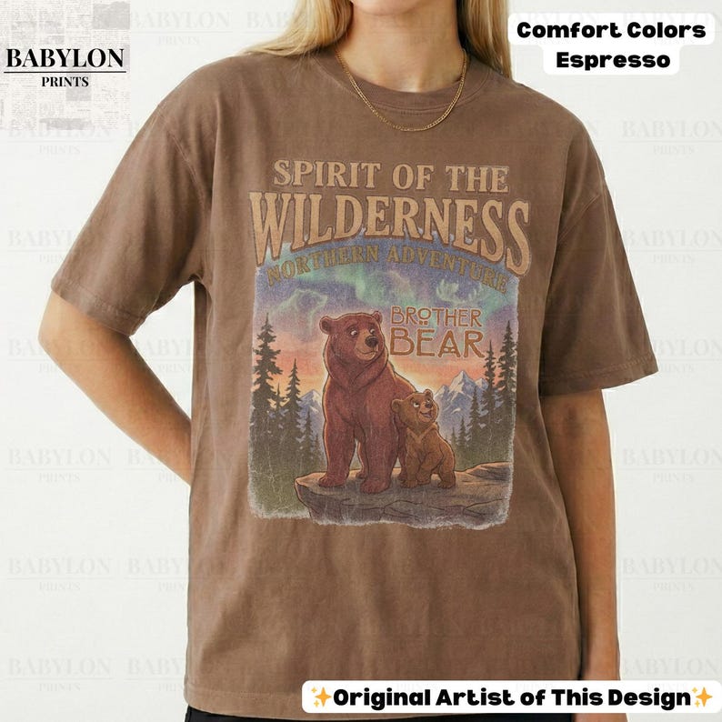 May include: Espresso-coloured t-shirt with a graphic of two bears and the text "Spirit of the Wilderness" and "Brother Bear." The design includes a mountain and forest scene. The shirt is from Babylon Prints.