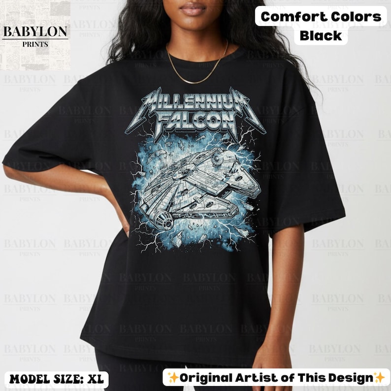 May include: Black t-shirt featuring a Millennium Falcon graphic with blue lightning bolts. The text "Millennium Falcon" is displayed above the spaceship design. The shirt is a comfort color and the model is wearing size XL.