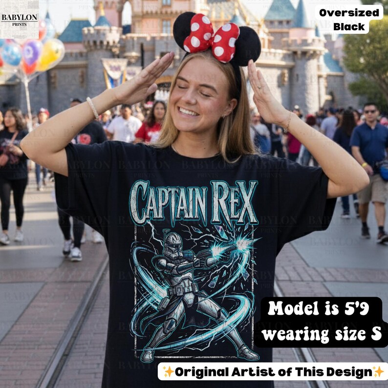 May include: Black oversized t-shirt with a Captain Rex graphic and the text "CAPTAIN REX". The shirt is worn by a person. The text "Original Artist of This Design" is also visible.