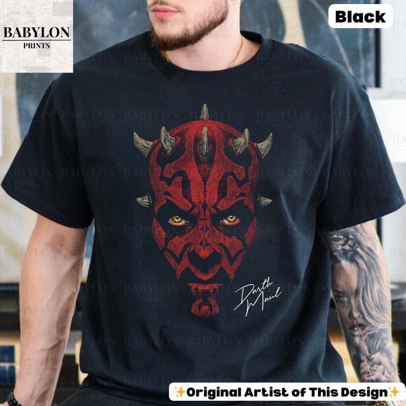 Może przedstawiać: Czarna koszulka z czerwoną grafiką twarzy Darth Maula, z ż&oacute;łtymi oczami i rogami. Tekst "Darth Maul" jest napisany białą czcionką. Koszulka ma u dołu napis "Original Artist of This Design".