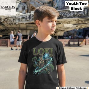 May include: Black youth tee featuring the word "LOKI" in green letters above a graphic of a character with green cape and horns, wielding blue energy. The shirt has the text "Youth Tee Black" in the upper right corner.