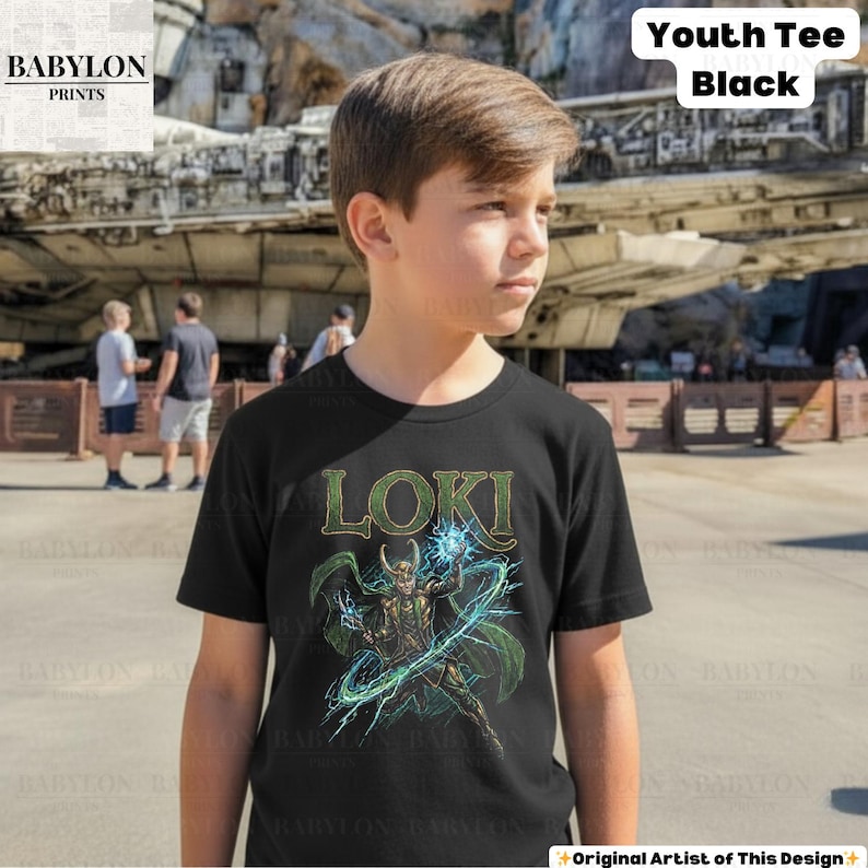 May include: Black youth tee featuring the word "LOKI" in green letters above a graphic of a character with green cape and horns, wielding blue energy. The shirt has the text "Youth Tee Black" in the upper right corner.