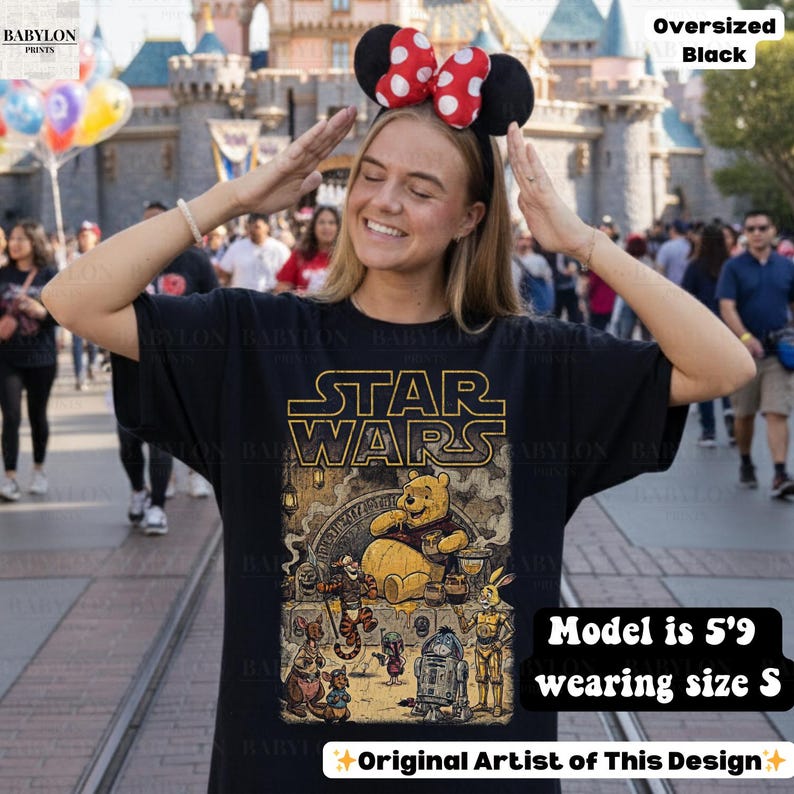 Może przedstawiać: Czarny, obszerny t-shirt z grafiką Star Wars i Kubusia Puchatka. Projekt zawiera napis "STAR WARS" złotymi literami i r&oacute;żne postacie. Modelka ma 1,75 m wzrostu i nosi rozmiar S.