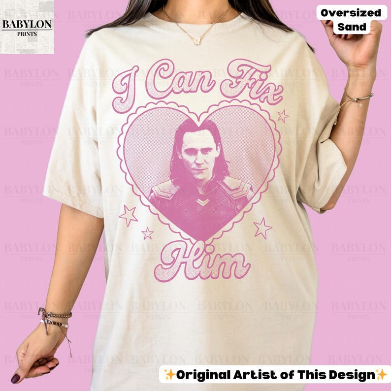 K&ouml;nnte beinhalten: &Uuml;bergro&szlig;es sandfarbenes T-Shirt mit rosa Grafik. Die Grafik zeigt ein herzf&ouml;rmiges Design mit dem Text "I Can Fix Him" und einem Portr&auml;t eines Mannes. Das Shirt hat auch den Text "Original Artist of This Design".