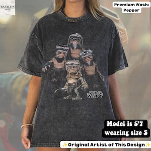 May include: A charcoal gray acid-wash t-shirt featuring a graphic print of four Ewok characters from Star Wars. The design includes the Star Wars logo in white text. The shirt has a crew neckline and short sleeves, showcasing a vintage-style wash.