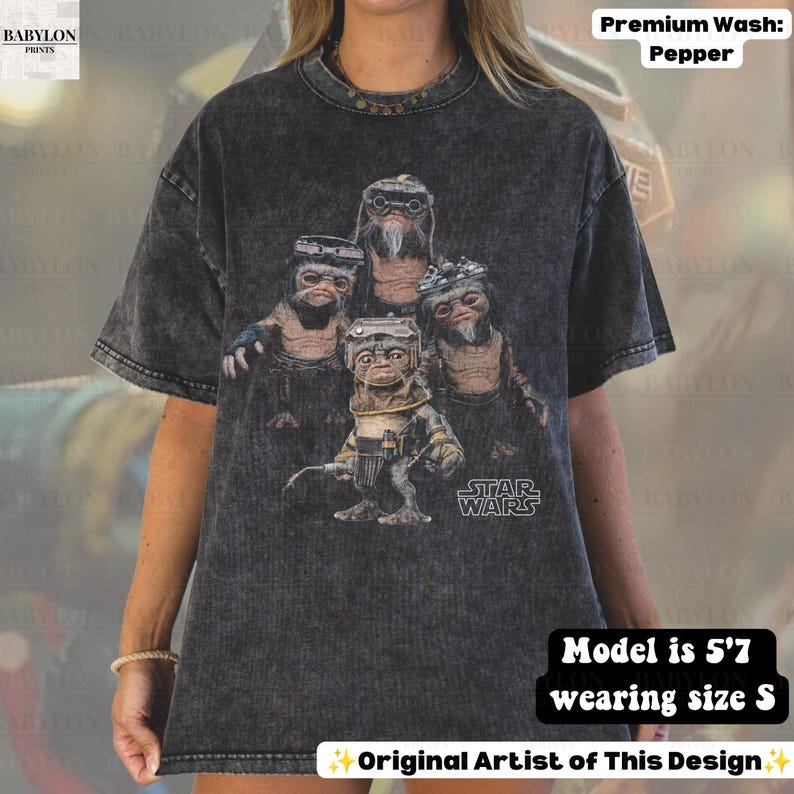 May include: A charcoal gray acid-wash t-shirt featuring a graphic print of four Ewok characters from Star Wars. The design includes the Star Wars logo in white text. The shirt has a crew neckline and short sleeves, showcasing a vintage-style wash.