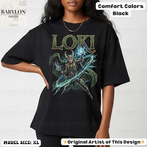 May include: Black t-shirt with a graphic of Loki, the Marvel Comics character, in green and gold. The word "LOKI" is printed above the character. The shirt is labeled "Comfort Colors" and "Original Artist of This Design."
