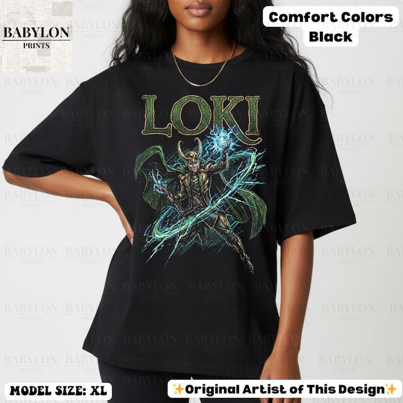 May include: Black t-shirt with a graphic of Loki, the Marvel Comics character, in green and gold. The word "LOKI" is printed above the character. The shirt is labeled "Comfort Colors" and "Original Artist of This Design."