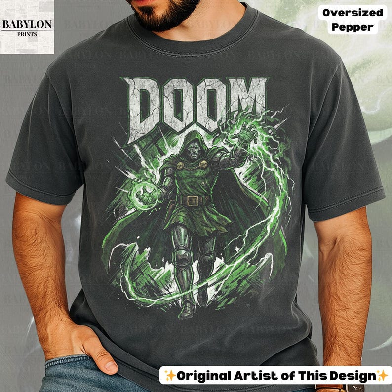 May include: Dark gray t-shirt featuring a graphic of a character from the comic book series, DOOM. The character is depicted in green and silver armor, with green energy effects. The word "DOOM" is printed in large, white, distressed letters above the character.