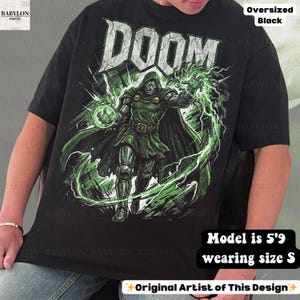 May include: Black oversized t-shirt featuring a graphic of Doctor Doom with green energy effects and the word "DOOM" in white. The shirt is a size S and the model is 5'9. The design is by the original artist.