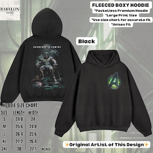 May include: Black fleece boxy hoodies with large print designs. One hoodie features a graphic of a character with the text "DOOMSDAY IS COMING." The other displays the Avengers logo. The size chart is included.