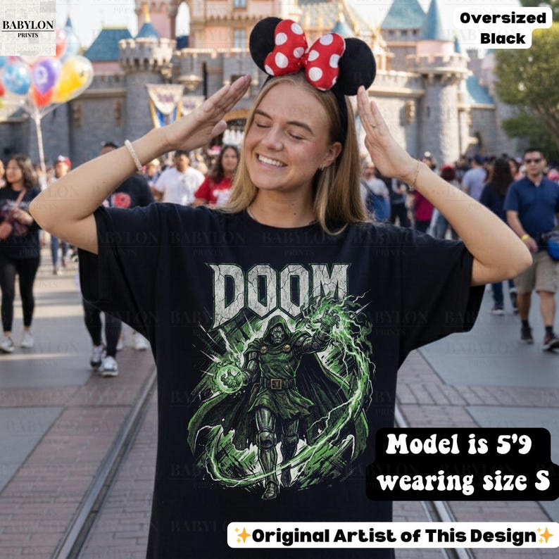May include: Black oversized t-shirt featuring the word "DOOM" in a distressed font, with a green and black graphic of a character. The text "Original Artist of This Design" is also visible. The model is 5'9" and wearing a size S.