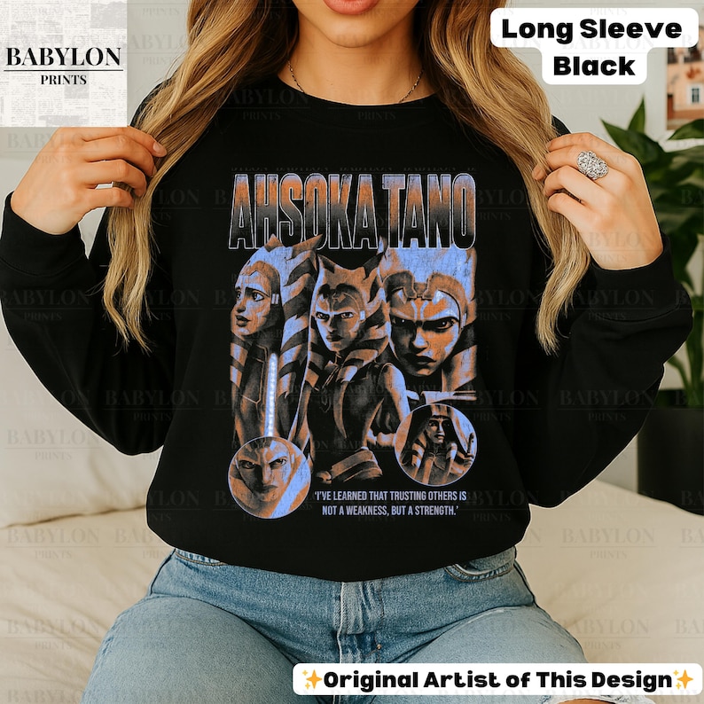 May include: Black long-sleeve sweatshirt with a graphic print of Ahsoka Tano from Star Wars. The graphic is in a vintage style with a blue and white color scheme. The text "I've learned that trusting others is not a weakness, but a strength." is printed below the graphic.