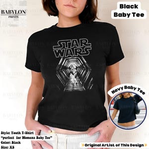May include: Black youth t-shirt featuring the Star Wars logo and a black and white graphic of a hallway. The shirt is a baby tee style. The text "STAR WARS" is in white block letters. The shirt is XS size.