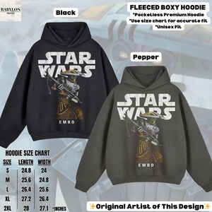 Puede incluir: Sudaderas con capucha boxy de forro polar negras y color pimienta con un gr&aacute;fico de Star Wars y el personaje Embo. Las sudaderas con capucha tienen un dise&ntilde;o sin bolsillo y est&aacute;n disponibles en varias tallas. La tabla de tallas muestra la longitud y el ancho en pulgadas.