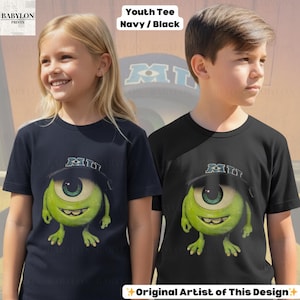 K&ouml;nnte beinhalten: Zwei Kinder tragen marineblaue und schwarze T-Shirts mit einer Cartoonfigur mit einem gro&szlig;en gr&uuml;nen Auge, einem Hut und den Buchstaben "MII". Die Shirts haben den Text "Youth Tee Navy / Black" und "Original Artist of This Design".