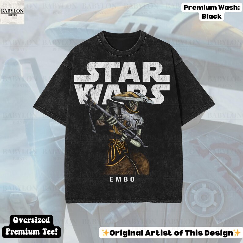 Puede incluir: Camiseta negra premium de gran tama&ntilde;o con el logo de Star Wars en blanco. La camiseta muestra una ilustraci&oacute;n del personaje Embo, sosteniendo un arma. El texto "EMBO" est&aacute; debajo del personaje. La camiseta est&aacute; etiquetada como "Premium Wash: Black" y "Oversized Premium Tee!"