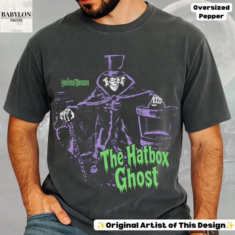 Puede incluir: Una camiseta gris carb&oacute;n de manga corta con un gr&aacute;fico de The Hatbox Ghost de The Haunted Mansion. El estampado muestra al personaje con sombrero de copa, bast&oacute;n y sombrerera, junto con el texto The Haunted Mansion y The Hatbox Ghost.