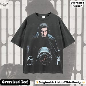 May include: Dark grey oversized tee with a graphic of a character from a science fiction film. The design includes a portrait and a helmet. The shirt has the text "Oversized Tee!" and "Original Artist of This Design".