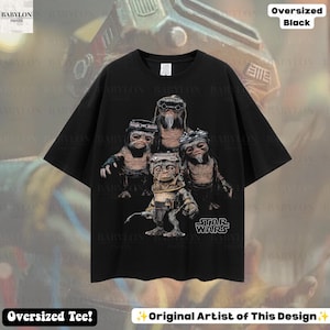 May include: An oversized black t-shirt featuring a graphic print of four Ewok characters from Star Wars. The characters are depicted in a group, with one standing in the foreground holding a tool. The Star Wars logo is printed in white at the bottom right.