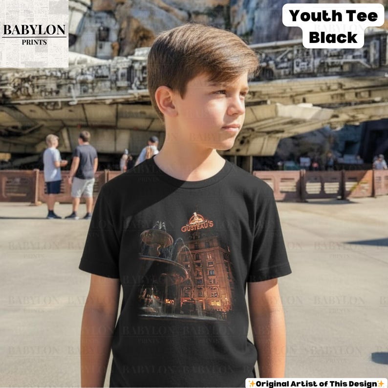 May include: Black youth tee with a graphic of a fountain and building, and the text "GUSTEAU'S". The shirt also has the text "Youth Tee Black". The Babylon Prints logo is in the upper left corner of the shirt.