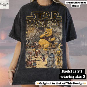 Może przedstawiać: Czarna koszulka z grafiką przedstawiającą Kubusia Puchatka i postacie z Gwiezdnych Wojen. Projekt zawiera ż&oacute;łty napis "STAR WARS". Koszulka jest prana w spos&oacute;b premium, a modelka ma 170 cm wzrostu i nosi rozmiar S. Oryginalny projekt artysty.