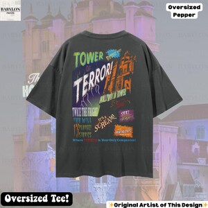 Op de afbeelding: Donkergrijs oversized T-shirt met een kleurrijk grafisch ontwerp. Het ontwerp bevat de woorden "TOWER OF TERROR!" en "HOLLYWOOD TOWER" met andere tekst en afbeeldingen. Het shirt heeft ook de tekst "Oversized Tee!"