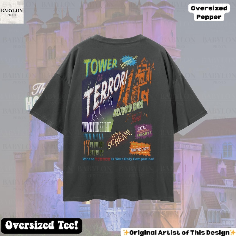 Op de afbeelding: Donkergrijs oversized T-shirt met een kleurrijk grafisch ontwerp. Het ontwerp bevat de woorden "TOWER OF TERROR!" en "HOLLYWOOD TOWER" met andere tekst en afbeeldingen. Het shirt heeft ook de tekst "Oversized Tee!"