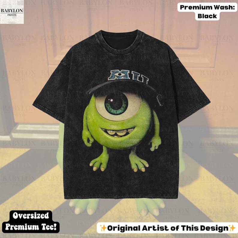 K&ouml;nnte beinhalten: Schwarzes, &uuml;bergro&szlig;es Premium-T-Shirt mit einer Cartoonfigur mit einem Auge, die einen Hut mit "MIU" tr&auml;gt. Die Figur ist gr&uuml;n mit einem gro&szlig;en Auge und einem l&auml;chelnden Mund. Das Shirt hat den Text "Premium Wash: Black" und "Oversized Premium Tee!"