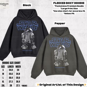 K&ouml;nnte beinhalten: Schwarze und pfefferfarbene Fleece-Hoodies mit Star Wars-Grafik von R2-D2. Die Hoodies haben eine gro&szlig;e Druckgr&ouml;&szlig;e und sind unisex. Die Gr&ouml;&szlig;entabelle zeigt die Ma&szlig;e in Zentimetern.