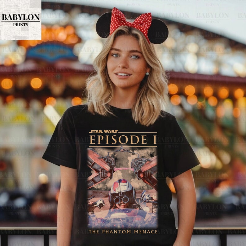 Op de afbeelding: Zwart T-shirt met een Star Wars Episode I-afbeelding. Het ontwerp bevat beelden uit de film, met de tekst "STAR WARS EPISODE I" en "THE PHANTOM MENACE". De persoon draagt een Minnie Mouse oren hoofdband.